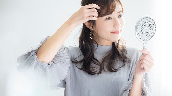 手鏡で髪型を確認する女性