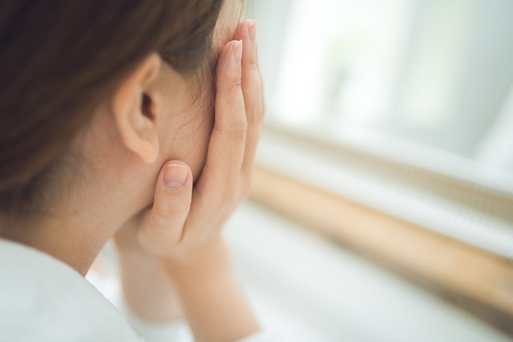 手で顔を覆う女性