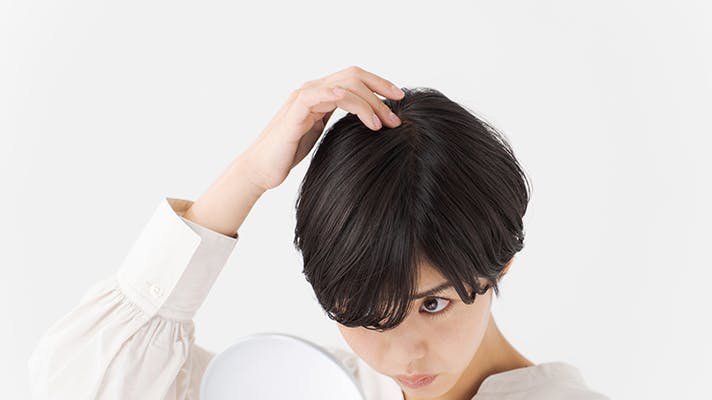 鏡でつむじを見る女性