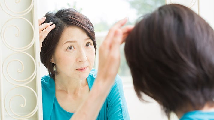 鏡の前で髪型を確認する女性