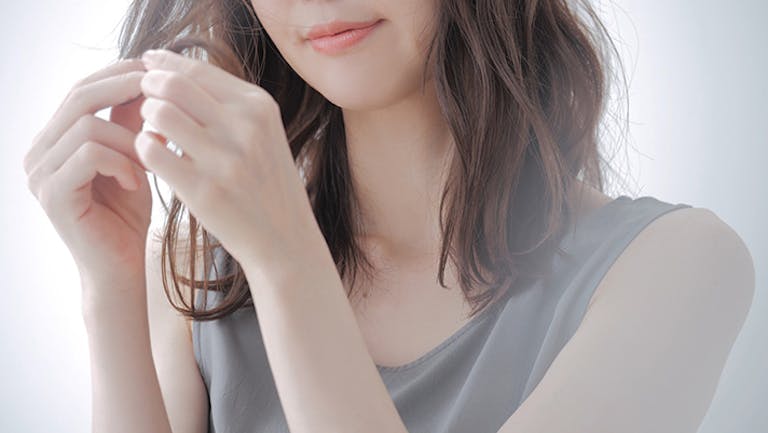 自分の髪を触る女性