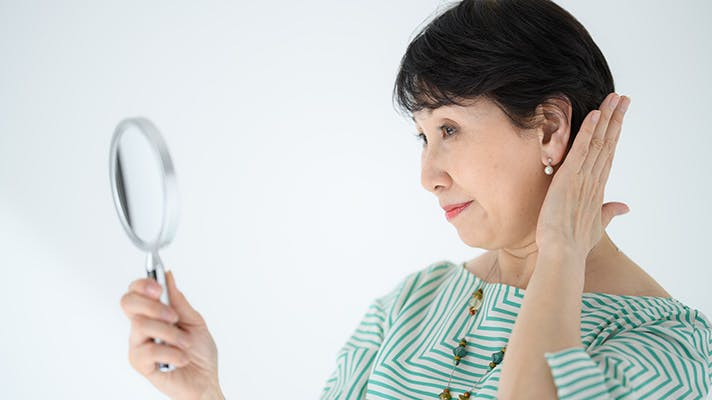 鏡で髪を確認する女性
