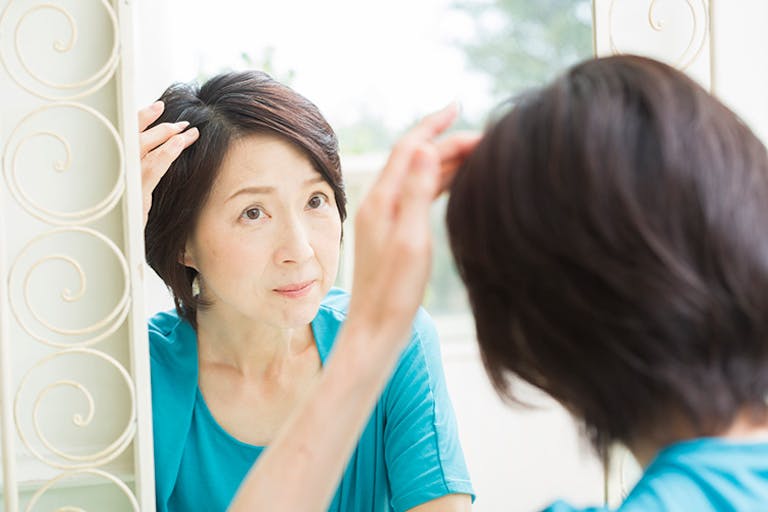 鏡の前で髪を触る女性