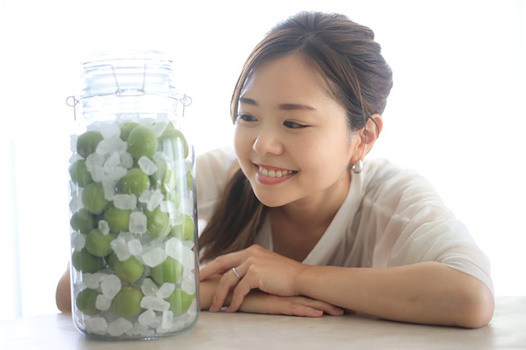 作ったフルーツシロップの瓶を見る女性