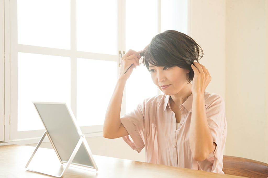 鏡を見ながら髪をとかす女性