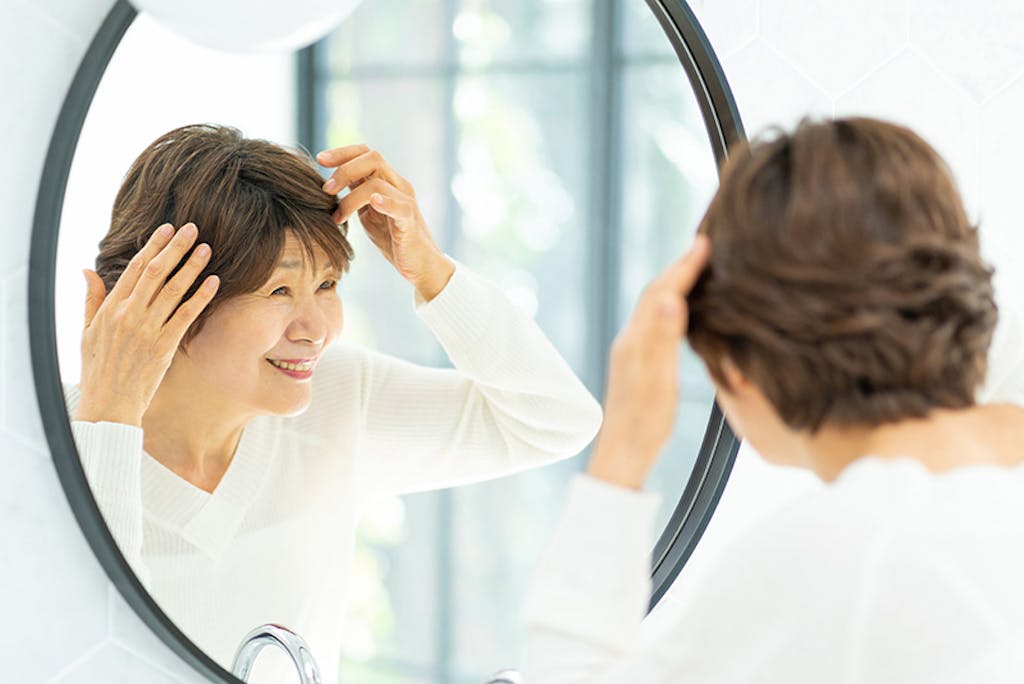 鏡を見ながら髪を整える女性