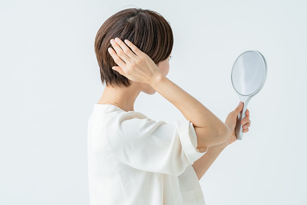 鏡で髪型を確認する女性